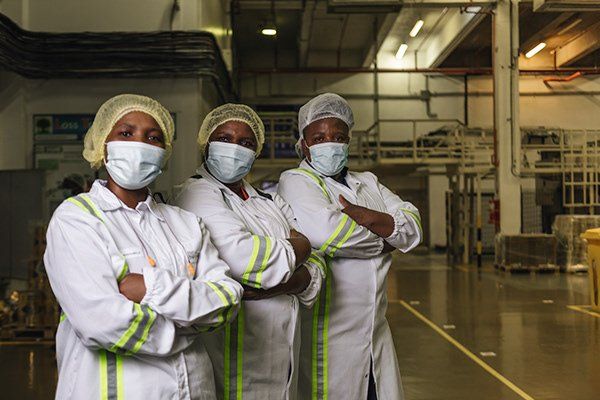 Three Nestlé employees in hairnets photographed on a factory floor