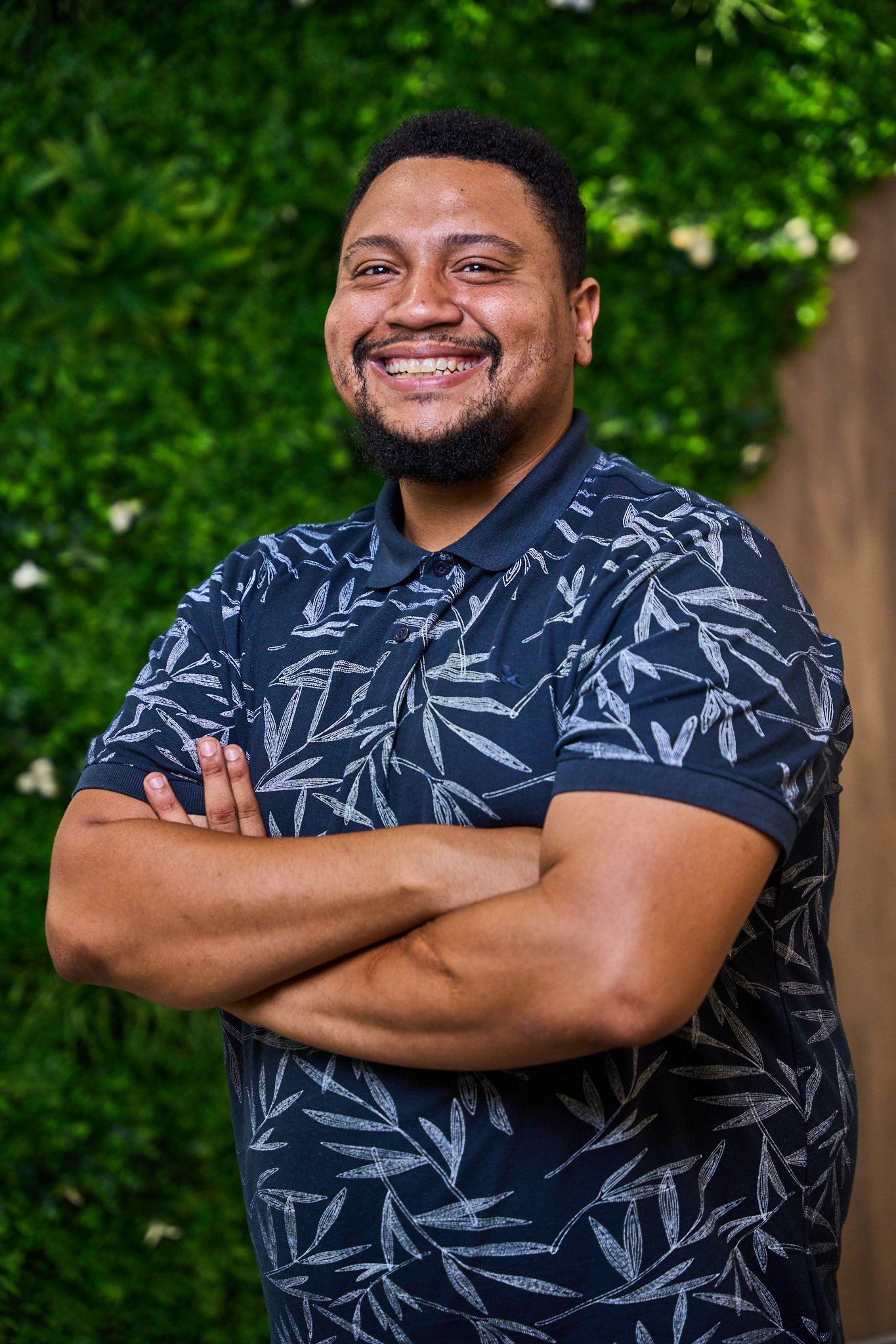 A man with his arms crossed in front of a living wall, from the Optimi web campaign